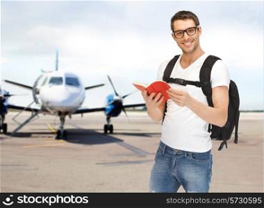 travel, education, tourism and people - smiling student with backpack and book at airport