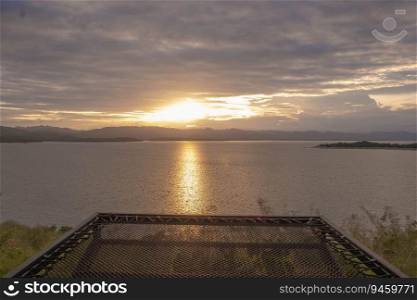 Travel for beautiful nature lake sunset with hammock, Relax vacation with landscape sky and evening sunlight, Calm outdoor holiday water reflection with cloud view background, peaceful calm horizon