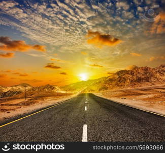 Travel forward concept background - road in Himalayas with mountains and dramatic clouds on sunset. Ladakh, Jammu and Kashmir, India