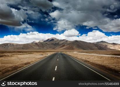Travel forward concept background - road on plains in Himalayas with mountains and dramatic clouds. Manali-Leh road, Ladakh, Jammu and Kashmir, India