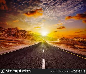 Travel forward concept background - vintage retro effect filtered hipster style image of road in Himalayas with mountains and dramatic clouds on sunset. Ladakh, Jammu and Kashmir, India. Road in Himalayas with mountains