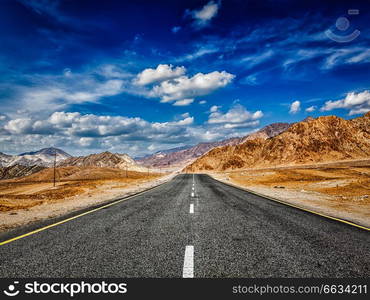 Travel forward journey concept - road in mountains Himalayas and dramatic clouds on blue sky. Ladakh, Jammu and Kashmir, India. Road in Himalayas with mountains