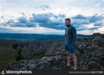 Travel, freedom and tourism concept - man standing on top of cliff in summer beauty evening in Altai mountains. Man standing on top of cliff