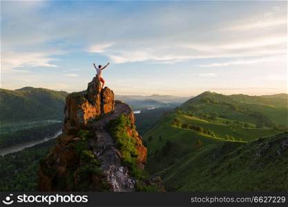 Travel, freedom leadership and real life concept - man standing on top of cliff in summer beauty sunset in Altai mountains. Man standing on top of cliff
