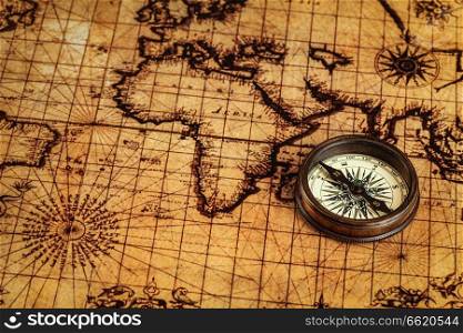 Travel geography navigation concept background - old vintage retro compass on ancient world map. Old vintage compass on ancient map