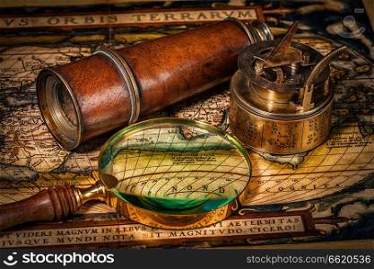 Travel geography navigation concept background - old vintage retro compass with sundial, spyglass and magnifying glass on ancient world map. Old vintage compass on ancient map