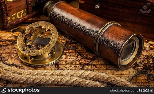 Travel geography navigation concept background - panorama of old vintage retro compass with sundial, spyglass and rope on ancient world map. Old vintage compass on ancient map