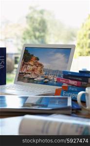 Travel guides next to laptop on table