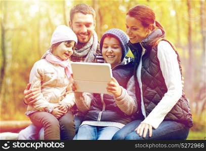 travel, hike and modern technology concept - happy family sitting on bench with tablet pc computer at camp in woods. family sitting on bench with tablet pc at camp