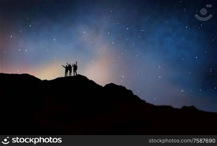 travel, hike and success concept - group of travelers or friends celebrating triumph on edge of mountain over starry night sky or space background. travelers celebrating success over night sky