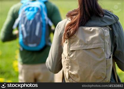 travel, hiking, backpacking, tourism and people concept - close up of couple with backpacks walking along country road