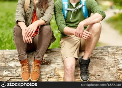 travel, hiking, backpacking, tourism and people concept - close up of couple resting on tree trunk outdoors