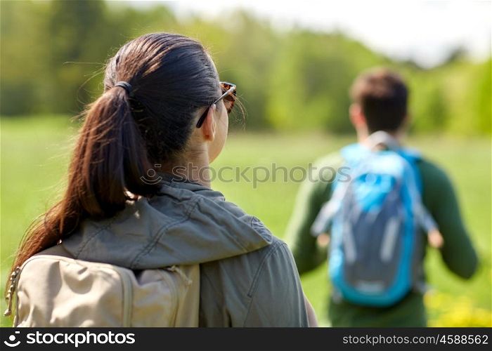 travel, hiking, backpacking, tourism and people concept - close up of couple with backpacks walking along country road