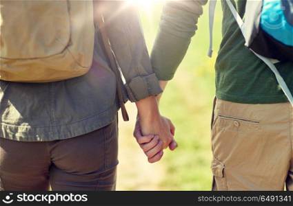 travel, hiking, backpacking, tourism and people concept - close up of couple with backpacks holding hands and walking along country road. close up of couple with backpacks holding hands. close up of couple with backpacks holding hands