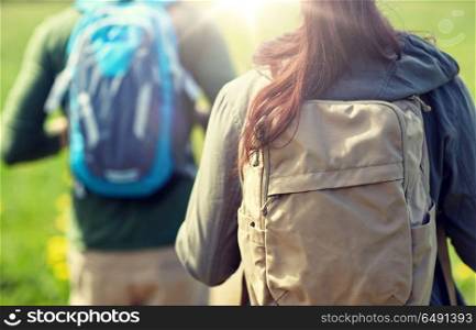 travel, hiking, backpacking, tourism and people concept - close up of couple with backpacks walking along country road. close up of couple with backpacks hiking outdoors. close up of couple with backpacks hiking outdoors