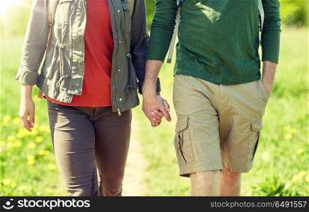 travel, hiking, backpacking, tourism and people concept - close up of couple with backpacks holding hands and walking along country road. close up of couple with backpacks holding hands. close up of couple with backpacks holding hands