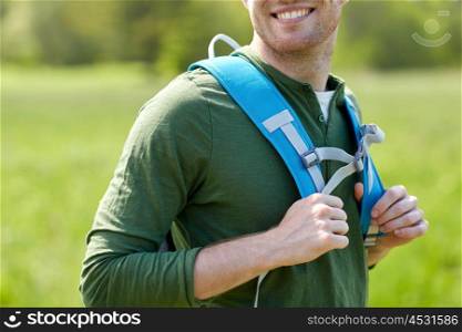 travel, hiking, backpacking, tourism and people concept - close up of happy young man with backpack walking outdoors