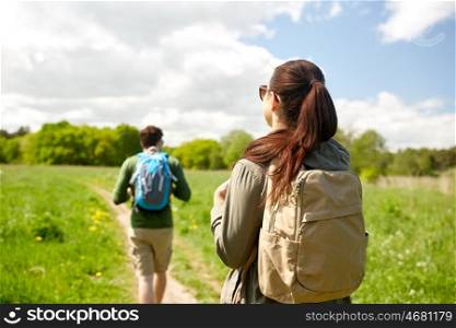 travel, hiking, backpacking, tourism and people concept - couple with backpacks walking along country road