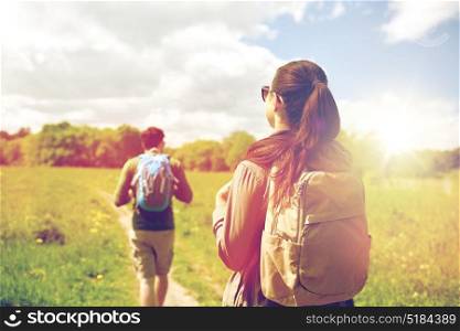 travel, hiking, backpacking, tourism and people concept - couple with backpacks walking along country road. happy couple with backpacks hiking outdoors