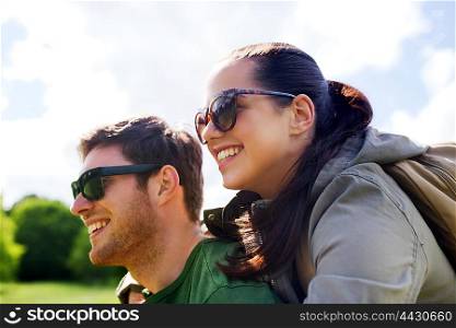 travel, hiking, backpacking, tourism and people concept - happy couple in sunglasses with backpacks having fun and hugging outdoors