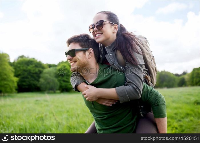 travel, hiking, backpacking, tourism and people concept - happy couple in sunglasses with backpacks having fun and walking along country road outdoors