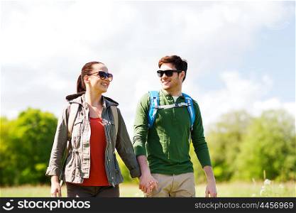 travel, hiking, backpacking, tourism and people concept - happy couple with backpacks holding hands and walking outdoors