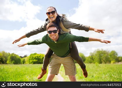 travel, hiking, backpacking, tourism and people concept - happy couple with backpacks having fun and walking along country road outdoors