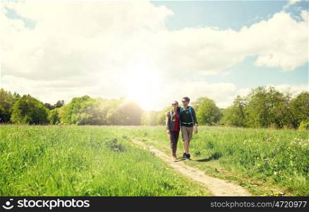 travel, hiking, backpacking, tourism and people concept - happy couple with backpacks hugging and walking along country road. happy couple with backpacks hiking outdoors. happy couple with backpacks hiking outdoors