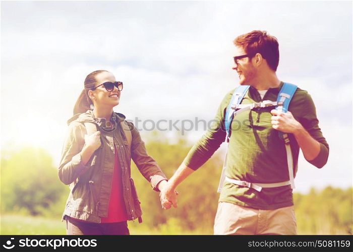 travel, hiking, backpacking, tourism and people concept - happy couple with backpacks holding hands and walking outdoors. happy couple with backpacks hiking outdoors