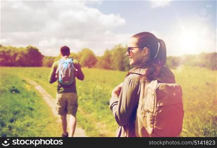 travel, hiking, backpacking, tourism and people concept - happy couple with backpacks walking along country road outdoors. happy couple with backpacks hiking outdoors