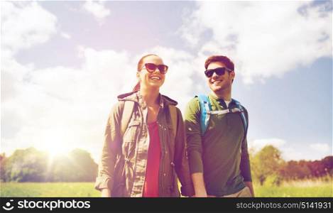 travel, hiking, backpacking, tourism and people concept - happy couple with backpacks holding hands and walking outdoors. happy couple with backpacks hiking outdoors