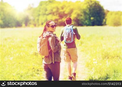 travel, hiking, backpacking, tourism and people concept - happy couple with backpacks walking along country road outdoors. happy couple with backpacks hiking outdoors