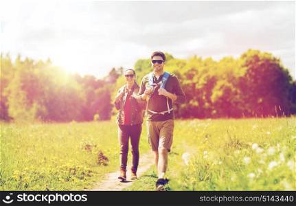 travel, hiking, backpacking, tourism and people concept - happy couple with backpacks and walking along country road outdoors. happy couple with backpacks hiking outdoors