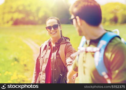 travel, hiking, backpacking, tourism and people concept - happy couple with backpacks holding hands and walking along country road outdoors. happy couple with backpacks hiking outdoors