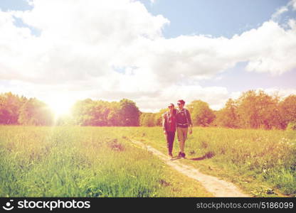 travel, hiking, backpacking, tourism and people concept - happy couple with backpacks hugging and walking along country road. happy couple with backpacks hiking outdoors