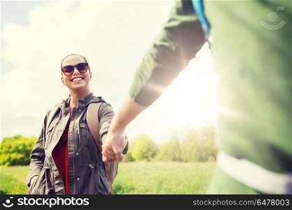 travel, hiking, backpacking, tourism and people concept - happy couple with backpacks holding hands and walking outdoors. happy couple with backpacks hiking outdoors. happy couple with backpacks hiking outdoors