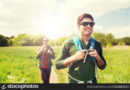 travel, hiking, backpacking, tourism and people concept - happy couple with backpacks walking along country road outdoors. happy couple with backpacks hiking outdoors. happy couple with backpacks hiking outdoors