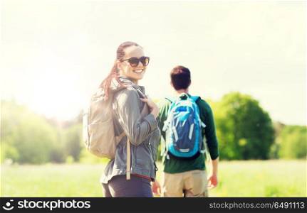 travel, hiking, backpacking, tourism and people concept - happy couple with backpacks walking along country road outdoors. happy couple with backpacks hiking outdoors. happy couple with backpacks hiking outdoors