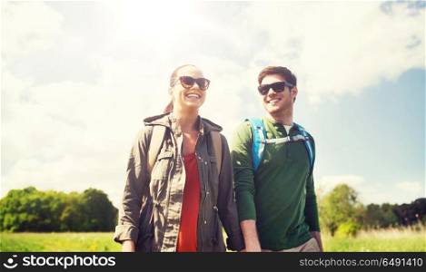travel, hiking, backpacking, tourism and people concept - happy couple with backpacks holding hands and walking outdoors. happy couple with backpacks hiking outdoors. happy couple with backpacks hiking outdoors