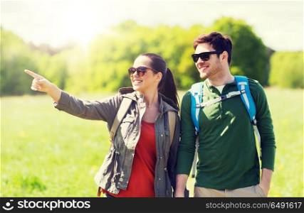 travel, hiking, backpacking, tourism and people concept - happy couple with backpacks walking outdoors and pointing finger to something. happy couple with backpacks hiking outdoors. happy couple with backpacks hiking outdoors