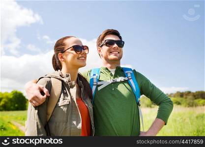 travel, hiking, backpacking, tourism and people concept - happy couple with backpacks hugging and walking outdoors
