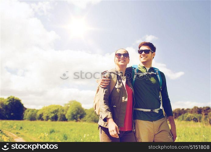 travel, hiking, backpacking, tourism and people concept - happy couple with backpacks hugging and walking outdoors. happy couple with backpacks hiking outdoors