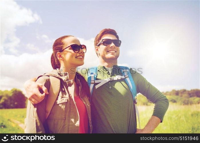 travel, hiking, backpacking, tourism and people concept - happy couple with backpacks hugging and walking outdoors. happy couple with backpacks hiking outdoors