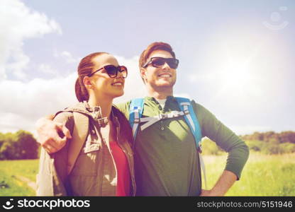 travel, hiking, backpacking, tourism and people concept - happy couple with backpacks hugging and walking outdoors. happy couple with backpacks hiking outdoors