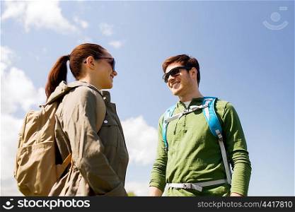travel, hiking, backpacking, tourism and people concept - happy couple with backpacks talking outdoors