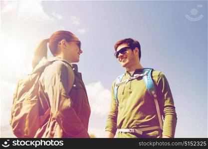 travel, hiking, backpacking, tourism and people concept - happy couple with backpacks talking outdoors. happy couple with backpacks hiking outdoors