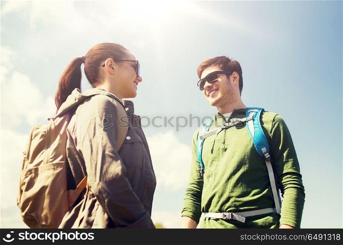 travel, hiking, backpacking, tourism and people concept - happy couple with backpacks talking outdoors. happy couple with backpacks hiking outdoors. happy couple with backpacks hiking outdoors