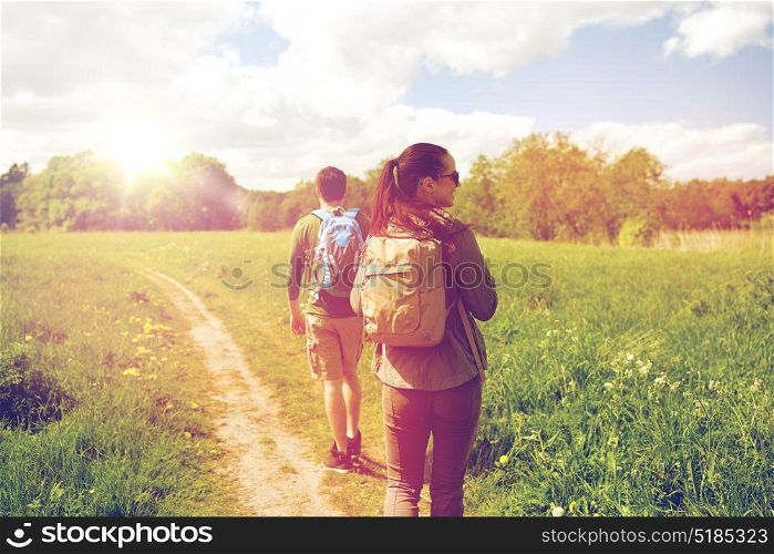 travel, hiking, backpacking, tourism and people concept - happy couple with backpacks walking along country road. happy couple with backpacks hiking outdoors
