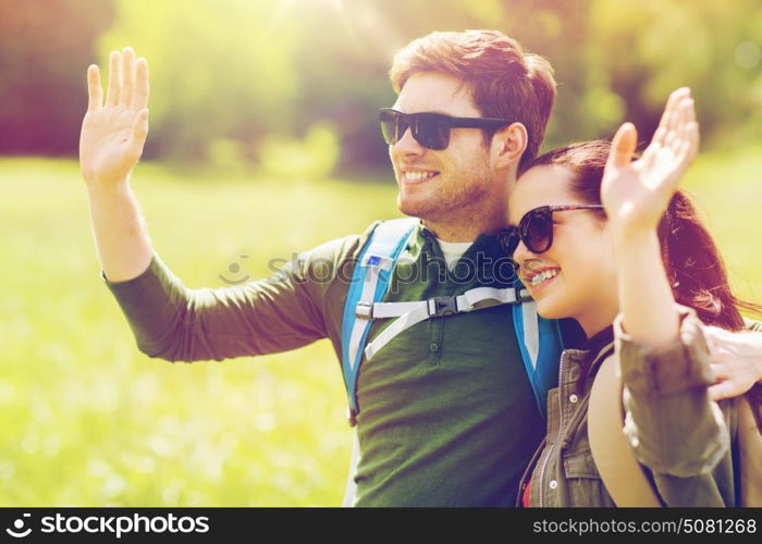 travel, hiking, backpacking, tourism and people concept - happy couple with backpacks waving hands outdoors. happy couple with backpacks hiking outdoors