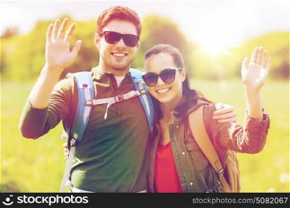 travel, hiking, backpacking, tourism and people concept - happy couple with backpacks waving hands outdoors. happy couple with backpacks hiking outdoors